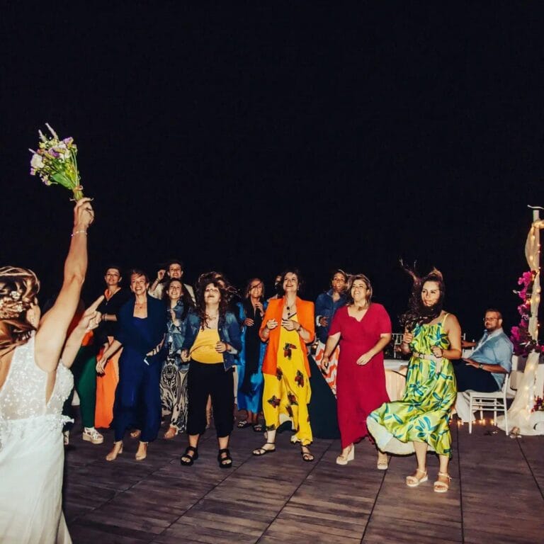 Wedding guests celebrating and dancing during bouquet toss moment at night party